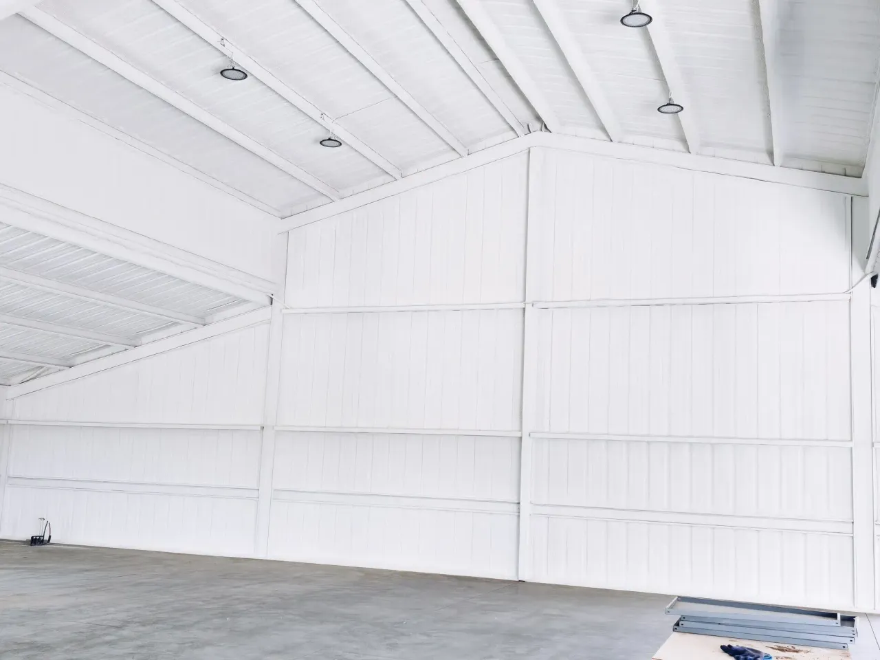 Empty white warehouse interior with closed-cell spray foam insulation on ceiling and wall