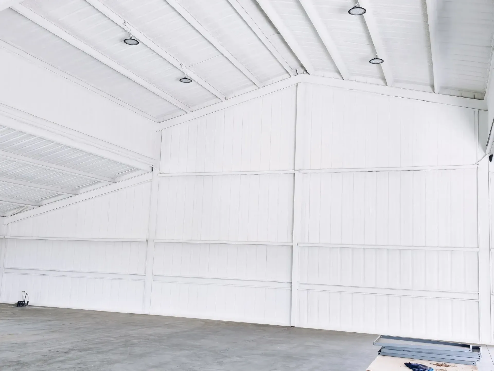 Empty white warehouse interior with closed-cell spray foam insulation on ceiling and wall